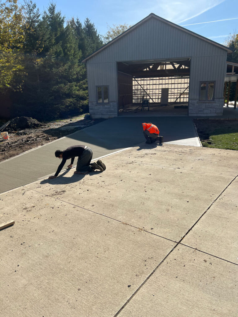 Men finishing a concrete driveway extension