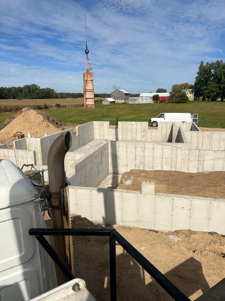 Poured concrete foundation and a crane hauling away concrete forms.